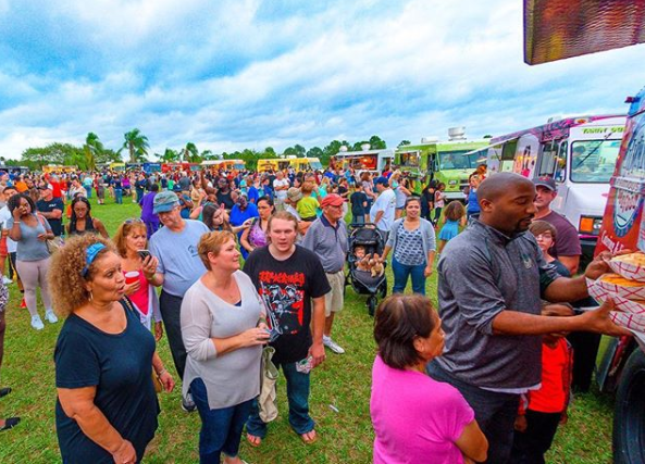 Crowd of guests lined up at food trucks during an outdoor food truck rally