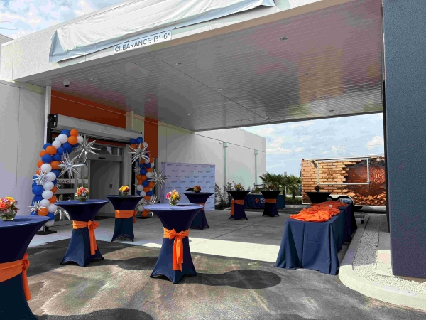 Event setup with a balloon arch, linen covered cocktail tables and a buffet